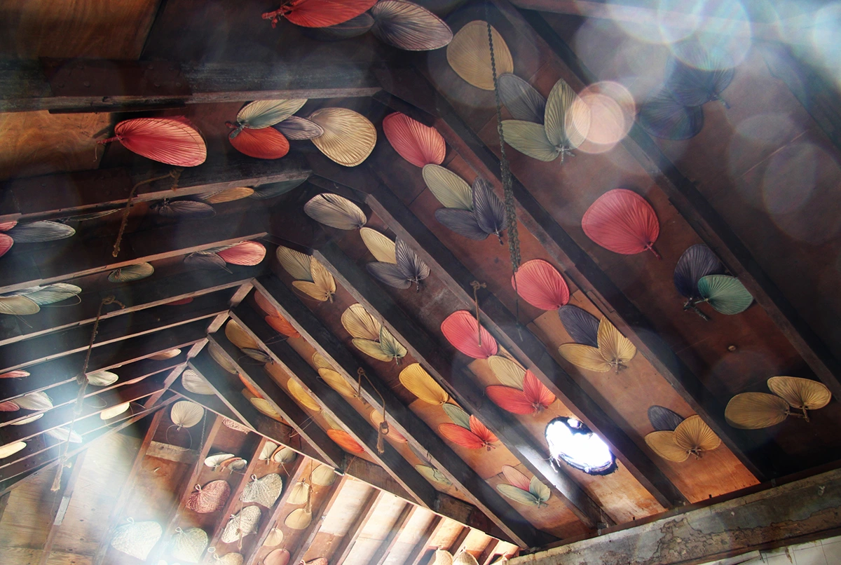 An outdoor bar features a ceiling still adorned with beautiful and colorful straw fans.