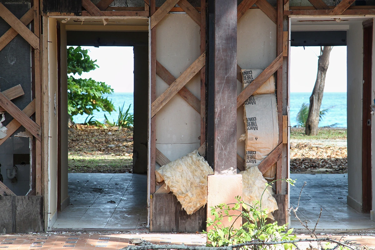 Most guest room doors, wooden siding, copper piping, and wiring were looted. This is a view looking through a ground level beach-front guest room.
