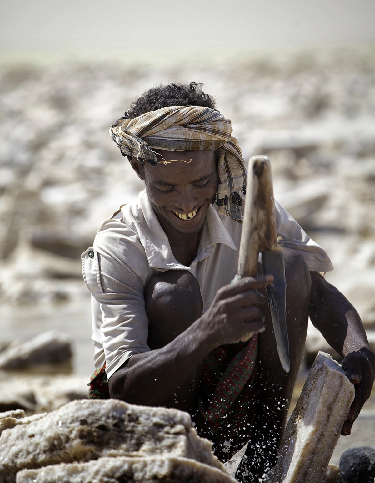 A salt miner chipping out blocks of salt for transport.