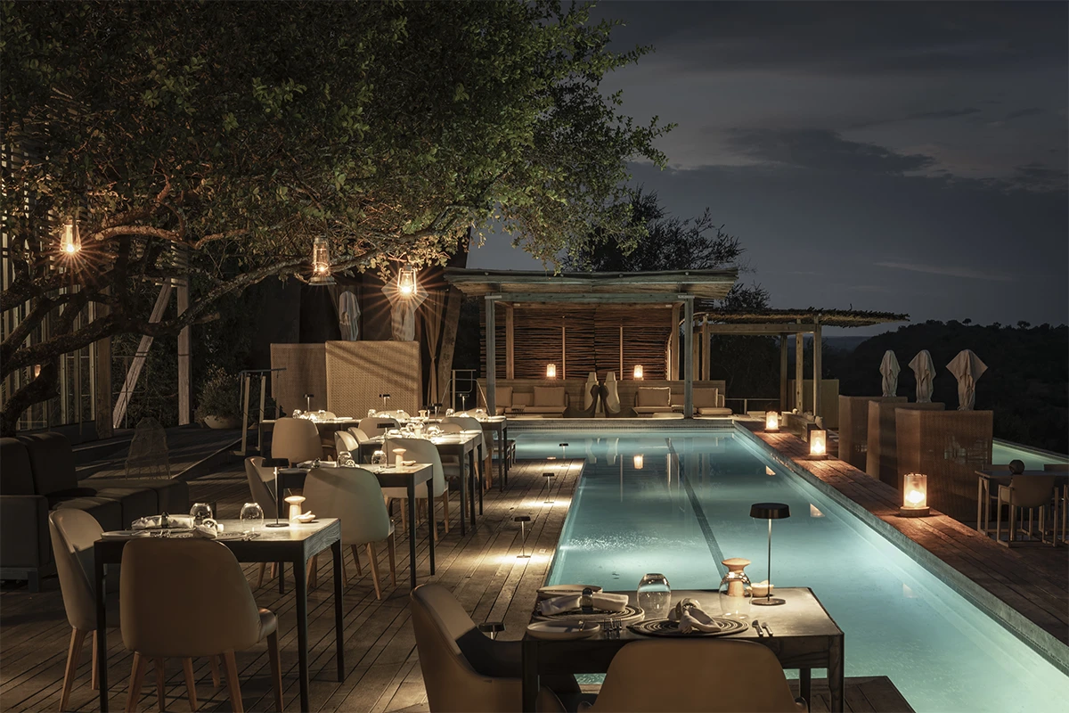 Outdoor dining terrace and pool at Singita Lebombo Lodge at night, Kruger National Park, South Africa